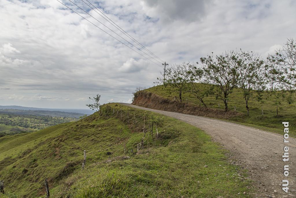 Bild Schotterstrasse mit Ausblick zeigt die Strasse auf einer Hügelkuppe und weiten Blick in die Landschaft
