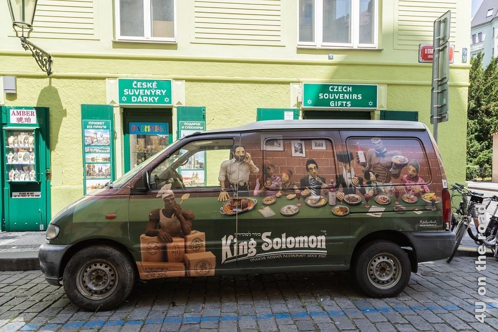 Bild Restaurantwerbung im jüdischen Viertel, Prag zeigt einen Van mit Personen an einer langen Tafel, die von muskulösen dunkelhäutigen Kellnern bedient werden. Die Werbung ist für King Solomons koscheres Essen.