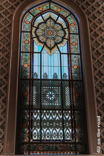 Das Fenster im Männergebetsraum der Sultan Qaboos Moschee, Muscat wirken wie gotische Kirchenfenster mit ornamentalem Bleiglas. Von aussen sind schattenspendende Verzierungen bis zur halben Höhe der Fenster angebracht.