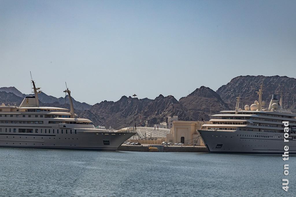 Muscat - Die Yachten des Sultans von der anderen Seite der Bucht gesehen. In diesem Bild wirkt es so, als wären die Yachten über Eck am Quai befestigt. Die eine Yacht hat ein Oberdeck weniger.