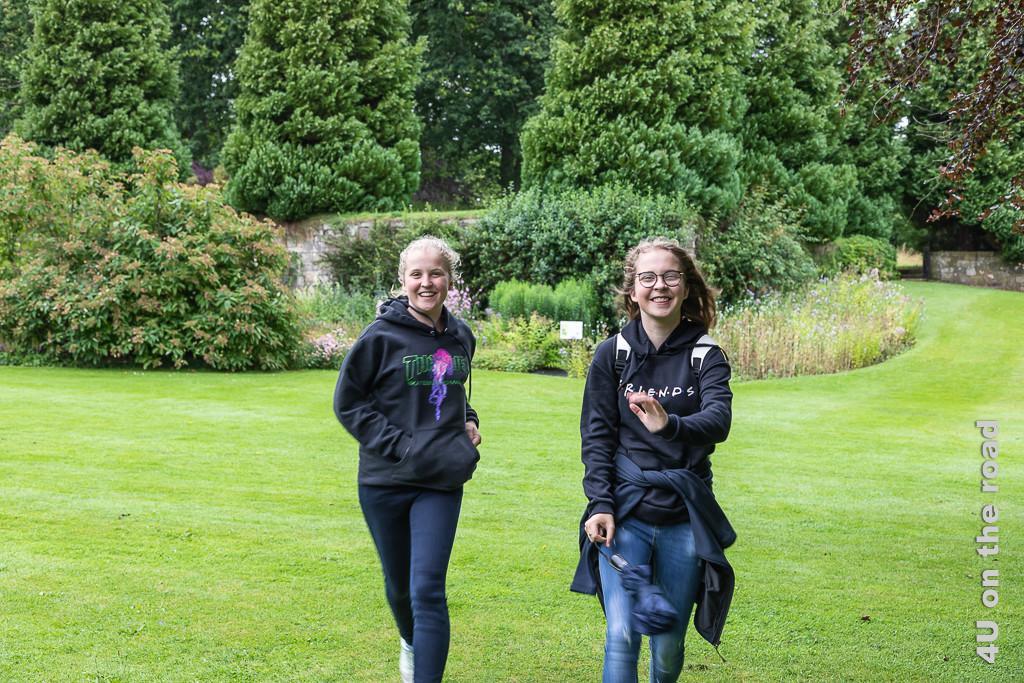 Die Mädchen nutzen den Park von Falkland Palace für einen Wettlauf. Im Vordergrund die rennenden Mädchen, im Hintergrund Blumenrabatten und Bäume.