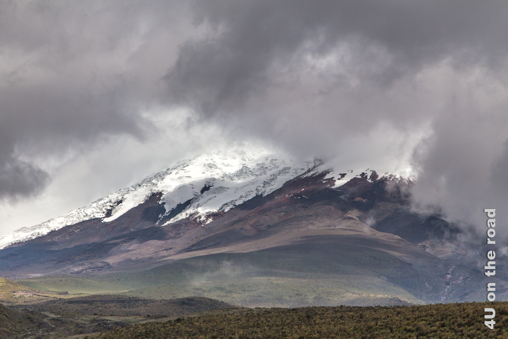 Die Wolkendecke am Cotopaxi Vulkan reisst kurz auf und lässt das rote Dach des Refugio José Rivas erkennen