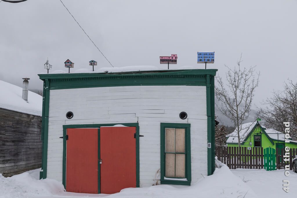 Originale Miniaturhäuser nach Häusern in Carcross auf dem Dach des Schuppens und hellgrün daneben die Tommy Brooks Cabin