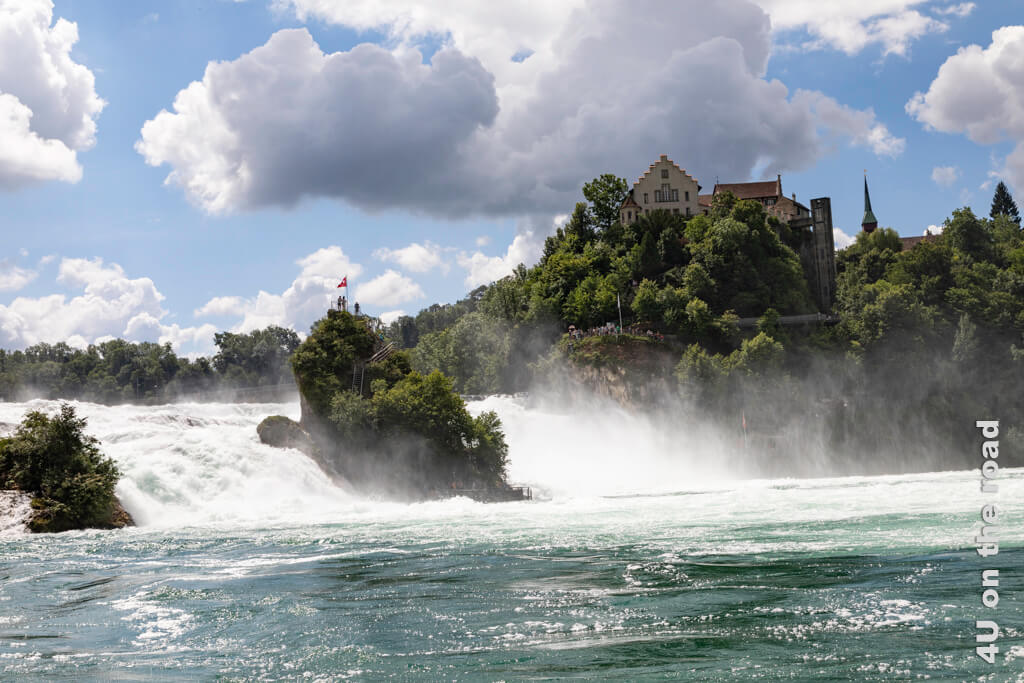 Im Bild ist der Fels mitten im Rheinfall und Schloss Laufen zu sehen. Das tosende Wasser des Rheinfalls ist von einer langen Fahne aus Sprühnebel umgeben. Du bekommst also nicht nur eine Abkühlung bei einem Bad in der Badi Bachdelle, sondern auch bei einer Bootsfahrt zum Känzeli.