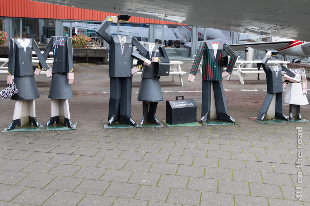 Skulpturen kopfloser Leute unter einer Tragfläche laden zum Fotografieren im Verkehrshaus der Schweiz ein.