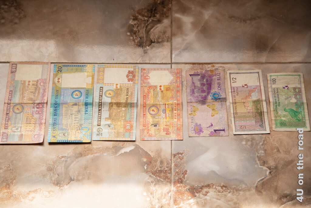 Die bunten Geldscheine des Omans auf einem gemusterten Mamorboden fotografiert.
