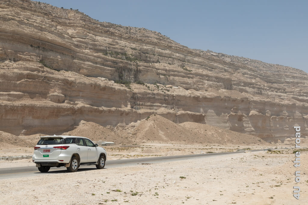 Unser weisser Toyota 4 x 4 Mietwagen  vor ausgewaschenen Sandsteinen. Oman Reisetipps Rundreise Mietwagen