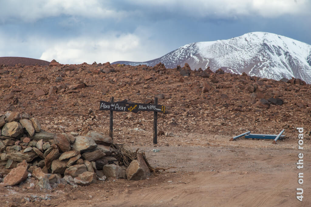 Im Bild ist das Schild der Passhöhe des Abra del Acay mit 4.895 m Höhe zu sehen. Im Hintergrund schaut ein schneebedeckter Berg hervor. - Reisetipps Argentinien von A bis Z