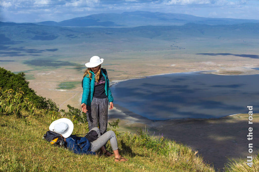 Die Mädchen helfen sich beim Aufstehen von ihrem Platz im Gras mit Aussicht - Wanderung am Ngorongoro Kraterrand
