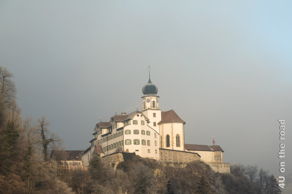 Kloster Werthenstein sitzt auf einem Felsvorsprung und wird bereits von der Sonne beschienen, während rundherum alles noch im Nebel ist.