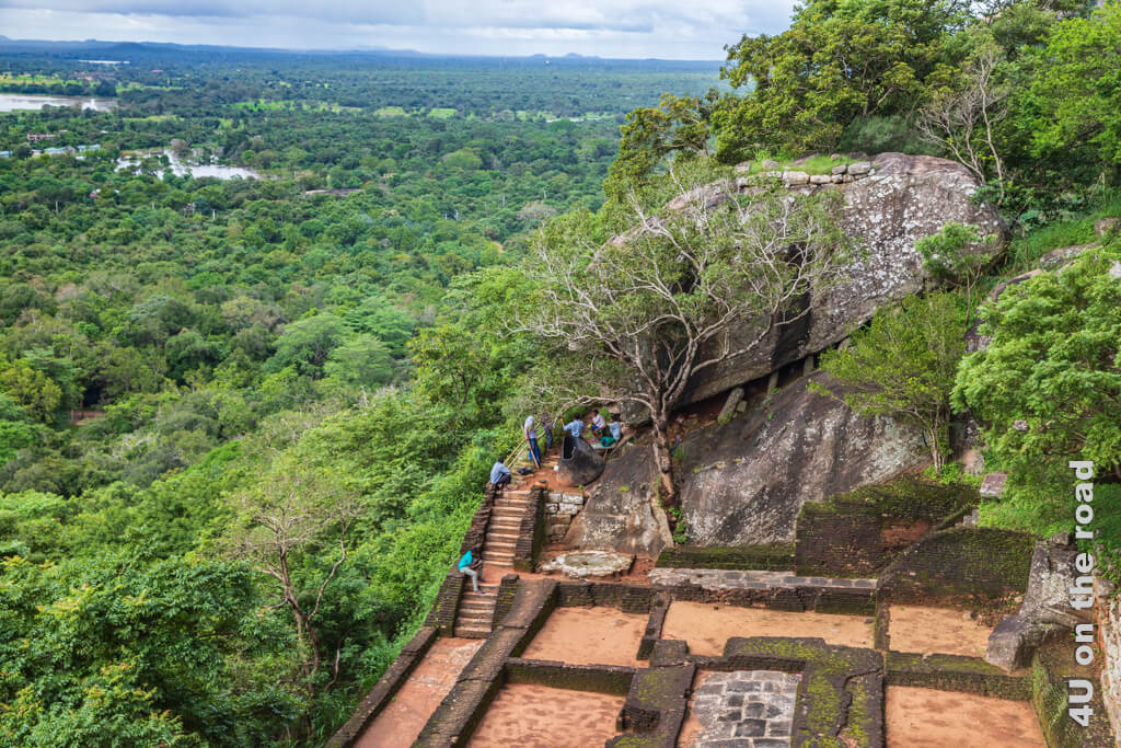 Bei einer Terrasse mit Fundamentresten ist ein grosser Felsbrocken zu sehen, der auf dünnen Steinstelzen steht. Dies ist der Verteidigungsstein, den man vom Sigiriya Felsen sieht.