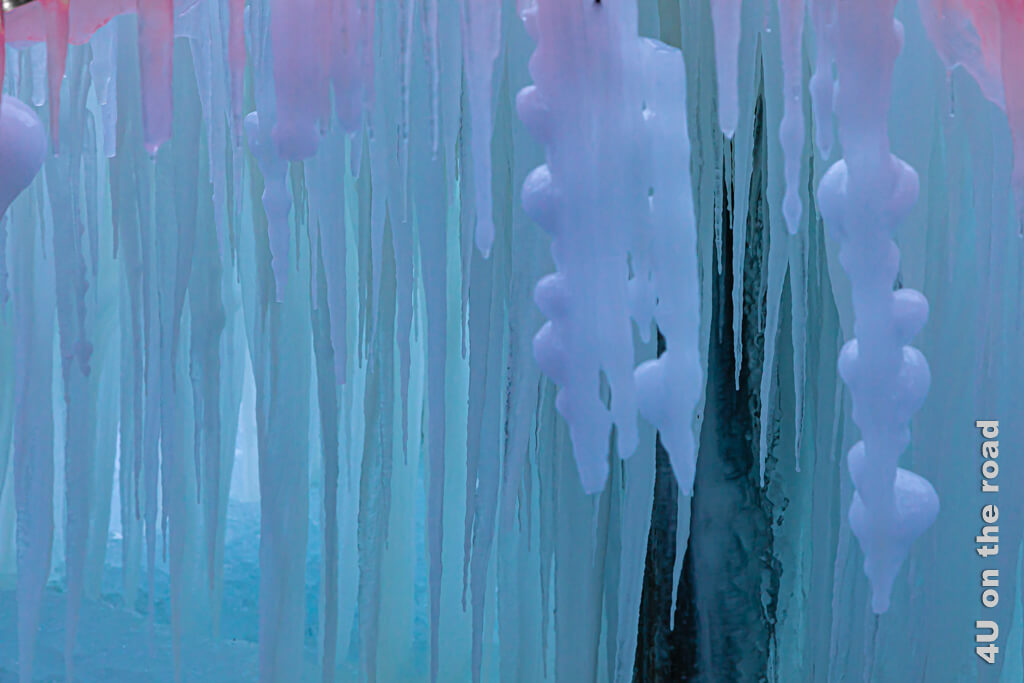 Durch indirekte blaue und rote Beleuchtung schimmern die Eiszahpfen von Türkis bis Violett.