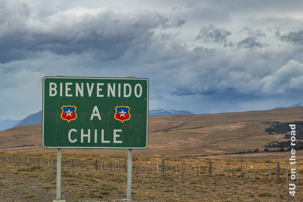 Das Schild Bienvenido a Chile steht scheinbar im Nirgendwo. Im Hintergrund erheben sich hohe Berge.