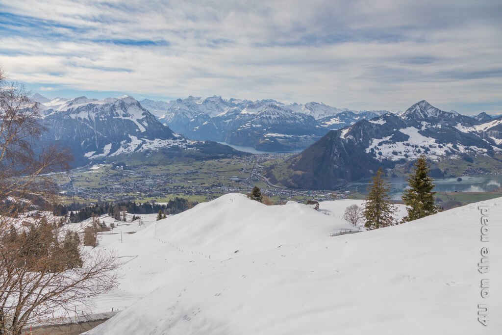 Berge mit Schnee und im grünen Tal Schwyz und die Ausläufer des Vierwaldstättersees und des Lauerzersees. Ausblick beim Winterwandern ab Sattel