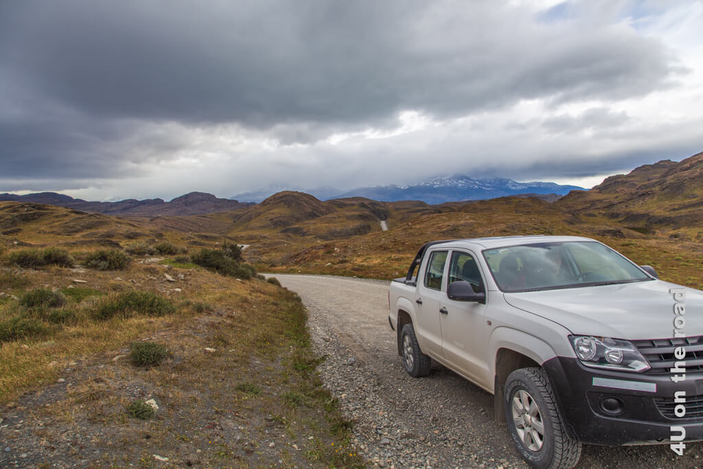 Der VW Amarok steht in der Landschaft des Torres del Paine Nationalpark. Tiefhängende Wolken verdecken die Sicht auf die Gipfel. Reisetipps Chile Mietwagen