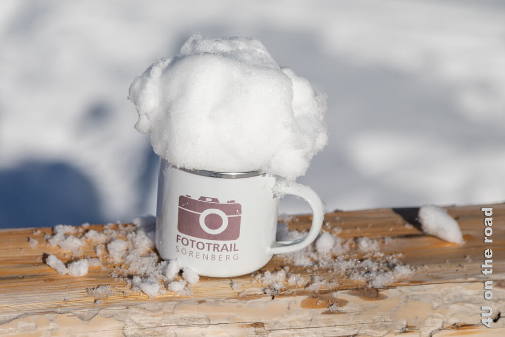 Eine Blechtasse mit Aufdruck Fototrail Sörenberg versehen wir mit einer Schnee-Schaumkrone.