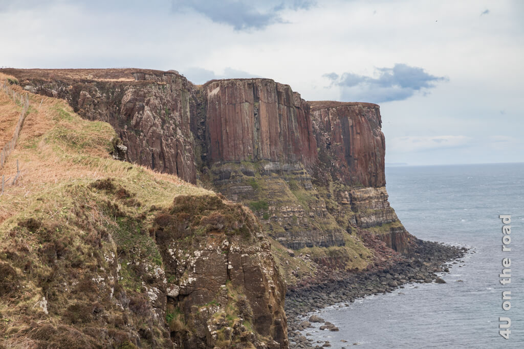 Diese Felsen bestehen im oberen Drittel aus Basaltsäulen, die sich von einem weicheren Sedimentgestein erheben, welches eher Quermuster aufweist. Der Wasserfall ist nicht in diesem Bild zu sehen. Diese Sehenswürdigkeit auf der Isle of Skye ist ein Touristen Hotspot.