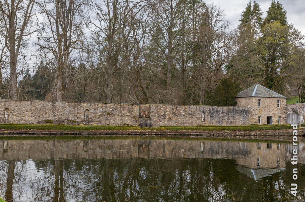 In der Mauer sind Vertiefungen für die Skulpturen im Herkules Garten von Blair Castle eingelassen. Die hohen Bäume hinter der Mauer spiegeln sich im Teich. Die von Buchs gefassten Beete sind noch leer.