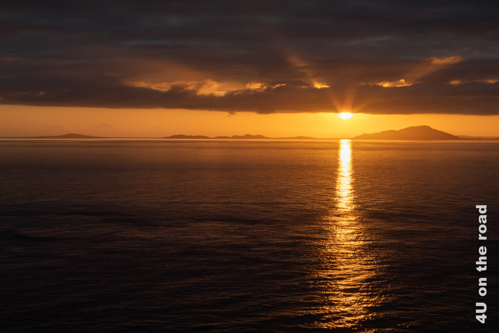 Die Sonne schaut halb aus den Wolken hervor und beleuchtet diese von unten. Alles ist in das orange Licht getaucht. Ein solcher Sonnenuntergang ist wirklich ein absolutes Highlight auf der Isle of Skye.