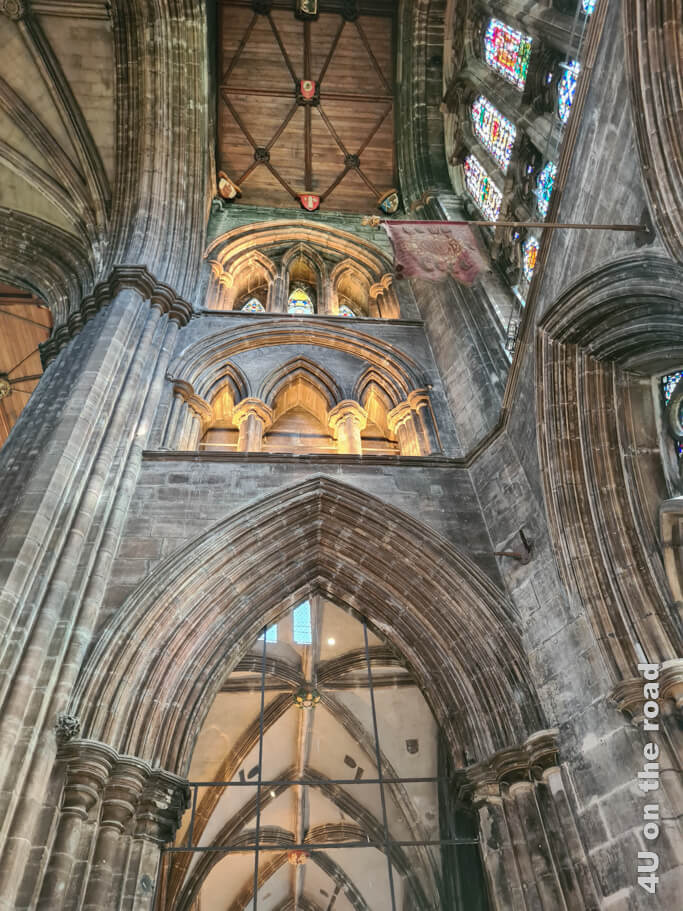 Eine andere Perspektive auf das Kreuzgewölbe, gotische Bögen, Buntglasfenster und Holzdecken.
