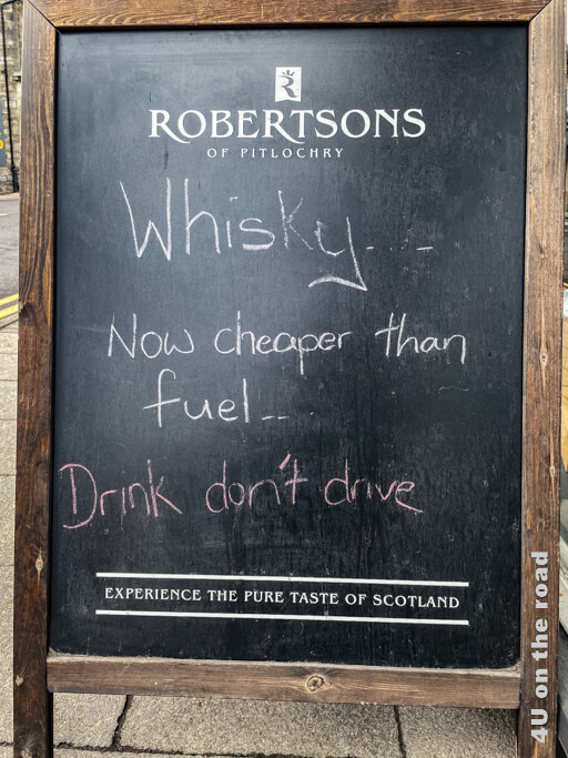 Tafel, auf der steht: Whisky ... Now cheaper than fuel. Drink don't drive.