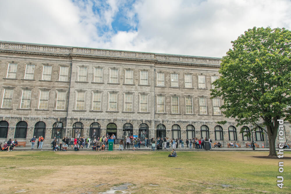 Das Gebäude, in dem sich das Book of Kells, eine der Sehenswürdigkeiten Dublins befindet, hat drei Etagen. Unzählige Menschen warten auf ihren Eintritt davor. 