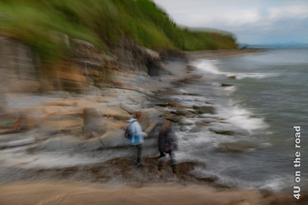 Eine Langzeitbelichtung zeigt andeutungsweise die Felsküste, das Meer und unsere beiden Töchter, die Steine ins Meer werfen.