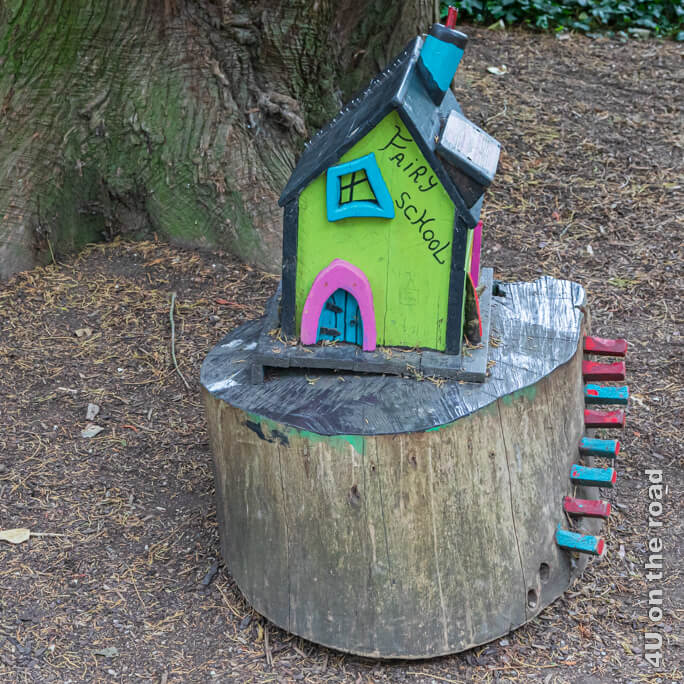Die Fairy Schule ist ein buntes Häuschen auf einem Baumstumpf mit einer rot-blauen Treppe.