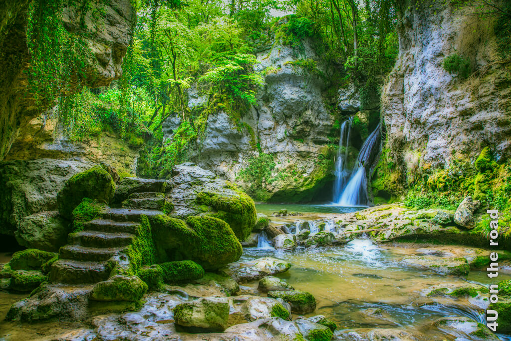 La Tine de Conflens ist eine Schlucht, in die ein Wasserfall mündet. In den Stein gehauene Treppen führen oberhalb des Wassers vorbei und sehen aus, wie lange vor unserer Zeit erschaffen. Alles ist bemoost und üppig Grün.