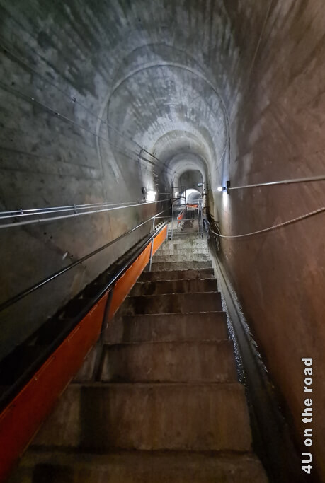 In diesem Tunnel der Staumauer Grande Dixence fliesst rechts und links Wasser neben den Treppenstufen. Die Stufen sind sehr hoch.
