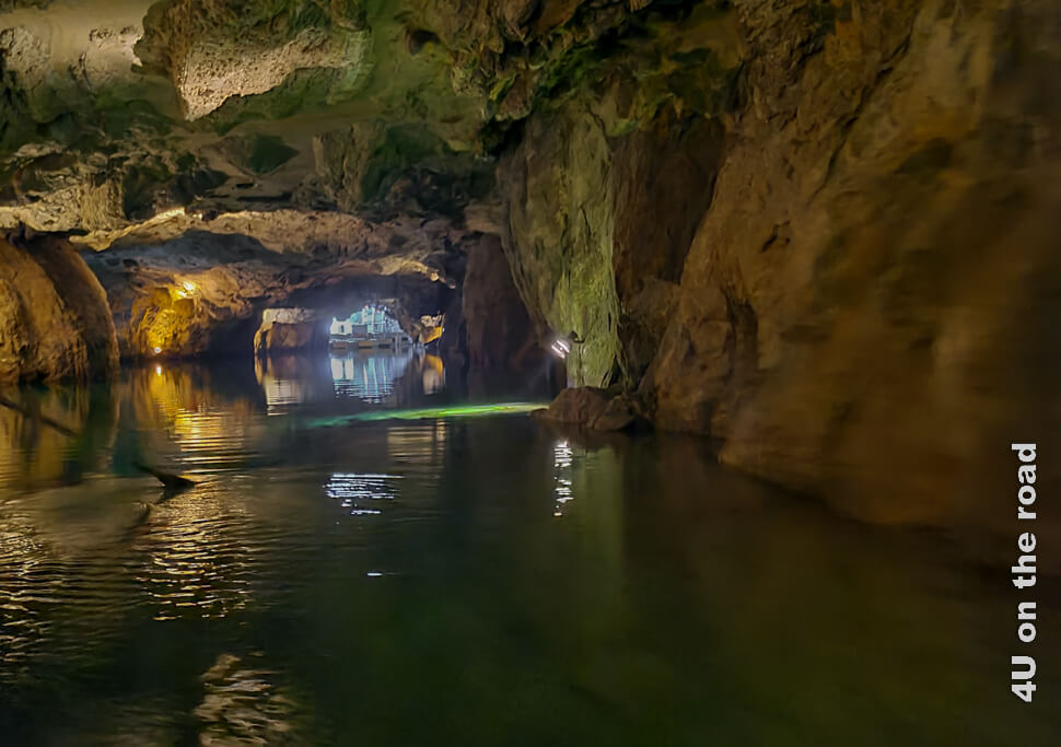 Im Licht der weissen Lampe wachsen grüne Algen auf den Steinen unter Wasser im unterirdischen See St. Léonard und färben das Wasser grünlich. Das Licht am Ausgang der Höhle leuchtet auch schon weiss ins Halbdunkel.
