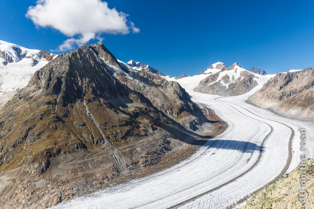 Blauer Himmel, ein Wölkchen und der Aletschgletscher, der sich in einer Kurve um die verschiedenen als Hörner bezeichneten Bergspitzen schiebt. Deutlich zu sehen, sind die beiden Mittelmoränen und ganz klein das Jungfraujoch. Gletscher in der Schweiz sind einfach zu erleben.