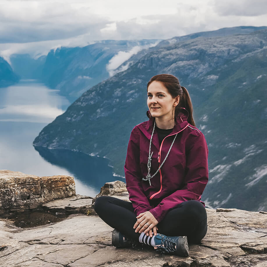 Marielle von My Travel Island sitzt auf einem Stein über einem Fjord