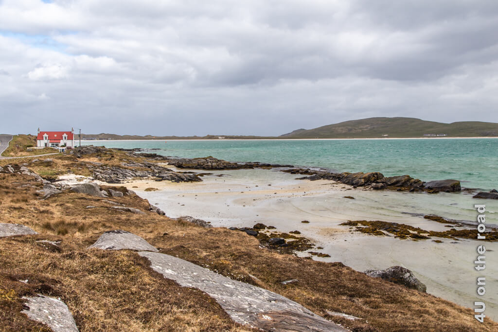 Barra, auf der Ringstrasse der Insel zeigt, Felsen, Moorboden, Sandstrand, Berge, türkisfarbenes Wasser und ein Haus mit rotem Dach. Das Bild ist so typisch für diese Insel der Äusseren Hebriden.
