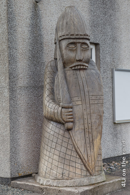 Ein grosser Berserker steht mit Schild, über welches er die oberen Zähne hängt und erhobenem Dolch vor dem Museum. Nachbildung der Schachfiguren, die auf der Insel Lewis gefunden wurden.