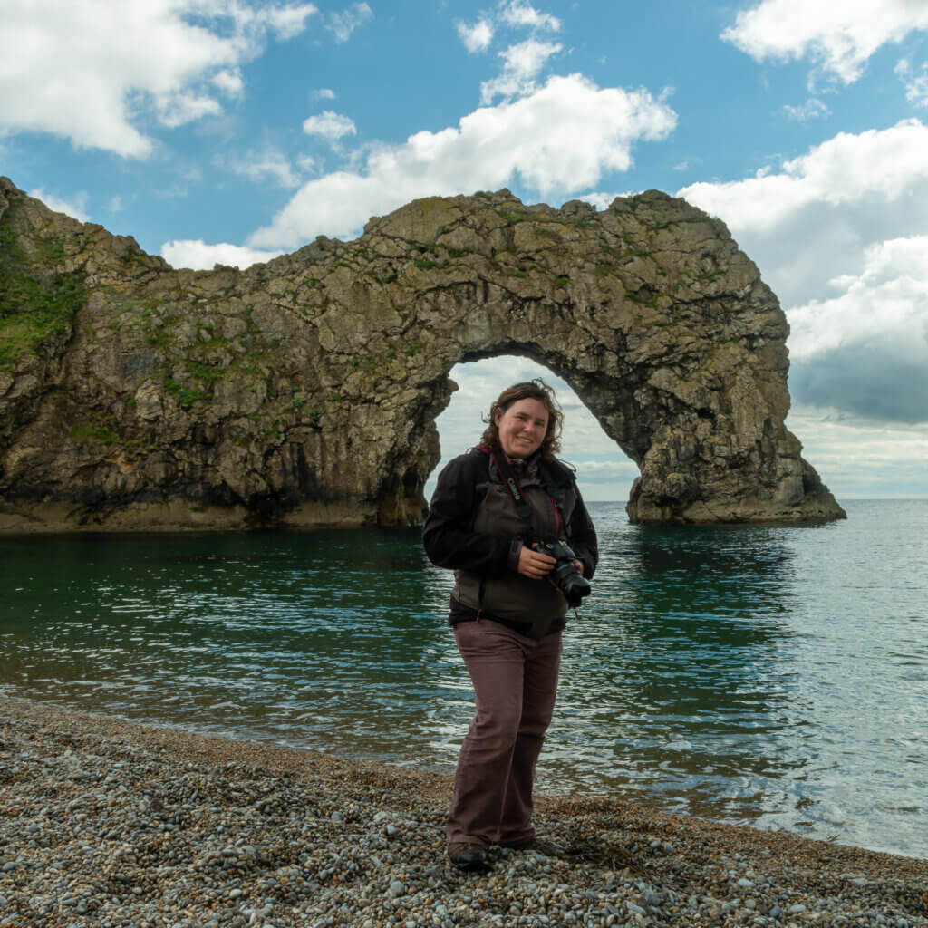 Kate von Kate Fish PhotoWalks vor einem Felsentor im Meer