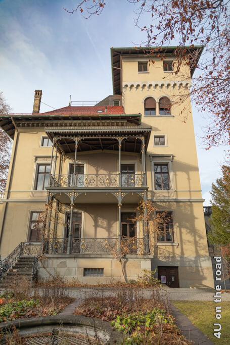Die Villa Tobler vom Garten aus gesehen mit schmiedeeisernen Balkonen und einem Turm. Die Villa Tobler ist ein echter Zürich Geheimtipp.