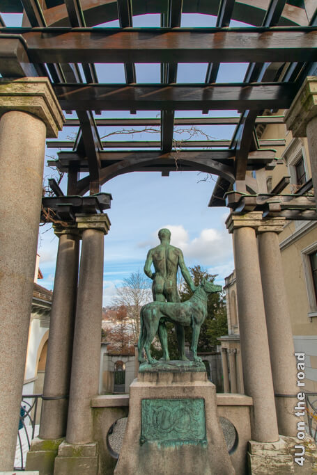 Die Bronze-Skulptur eines Mannes mit Hirsch mit grüner Patina blickt auf den Eingang der Villa Tobler.