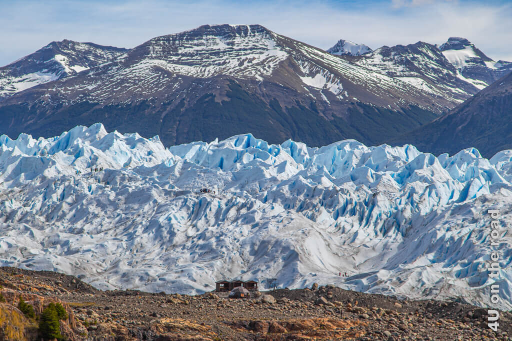 Seitenansicht mit den Hütten, in denen man die Steigeisen bekommt und drei Gruppen auf dem 80 km von El Calafate entfernten Perito Moreno Gletscher.