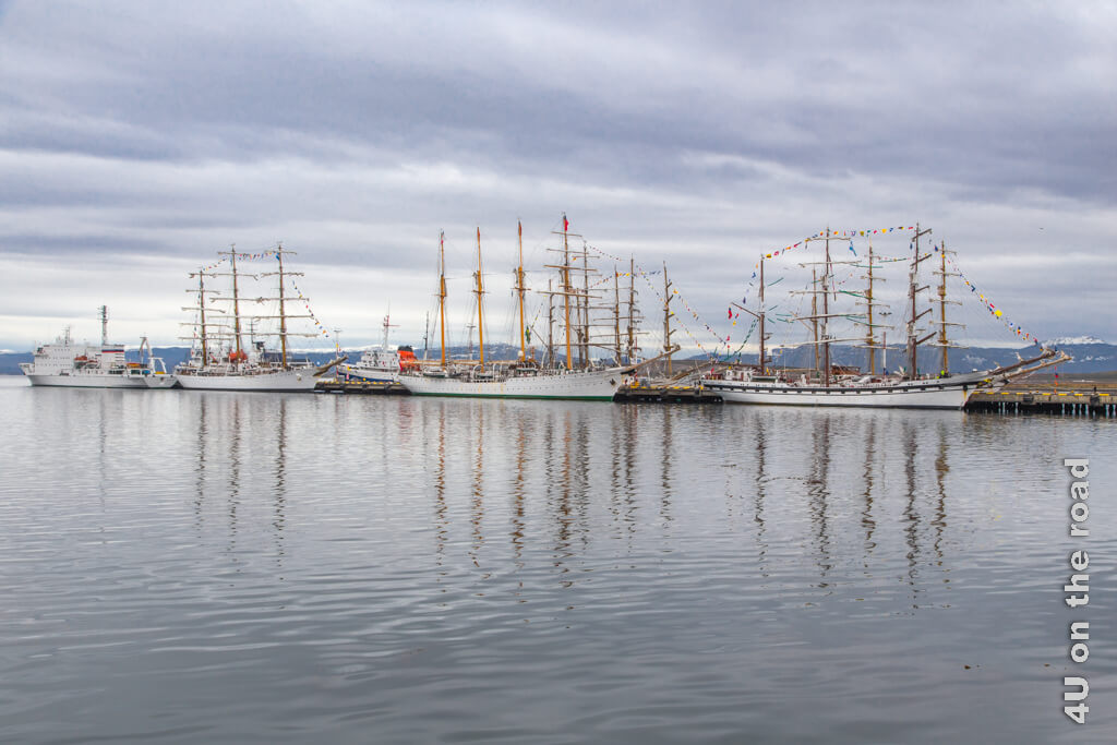 Segelschiffe mit drei bis vier Masten liegen im Hafen von Ushuaia. Ein Forschungsschiff, welches bald ausläuft, liegt ganz vorn.