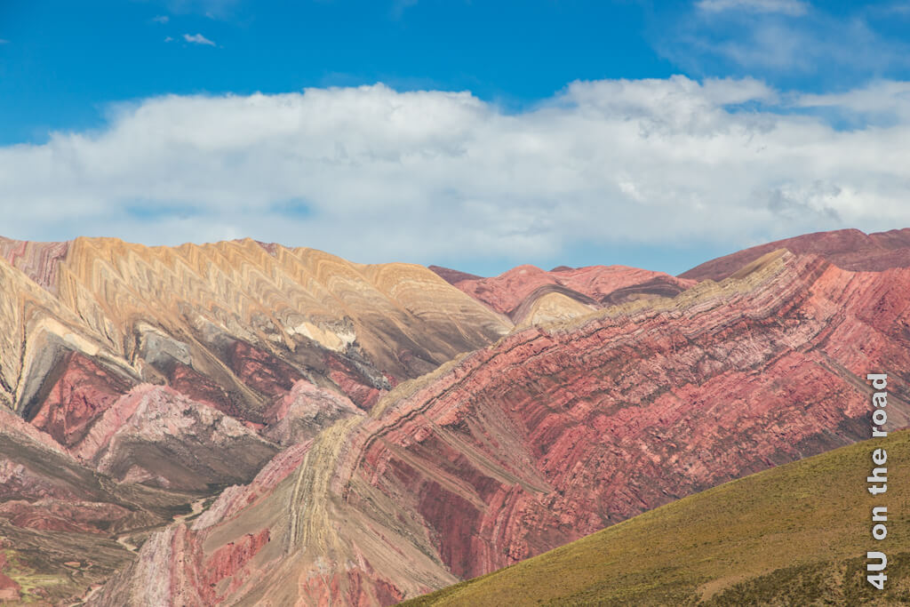 Vor den farbigen Dreiecken der Serranias del Hornocal steht ein gekippter Bergrücken, dessen viele Schichten man genau erkennen kann.