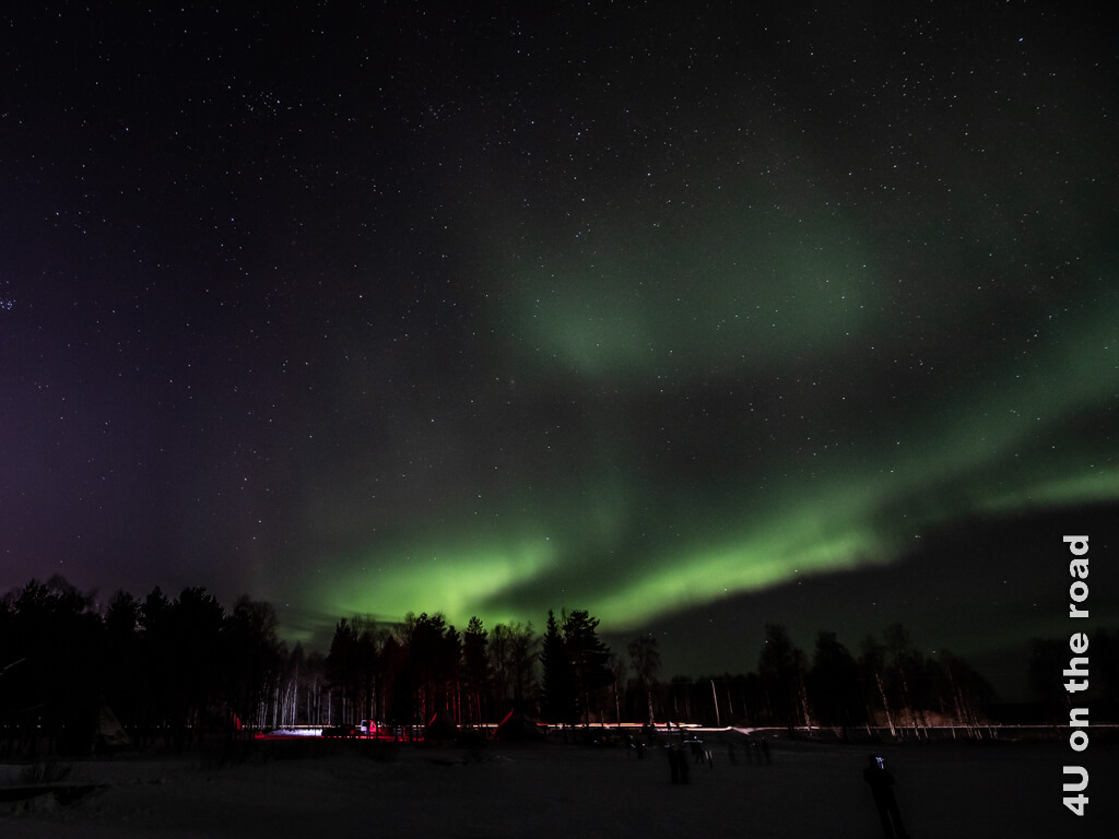 Polarlichter mit Millionen von Sternen am Himmel vom See am Aurora Hunting Olkarjärvi Parkplatz bei Rovaniemi, Finnland gesehen.