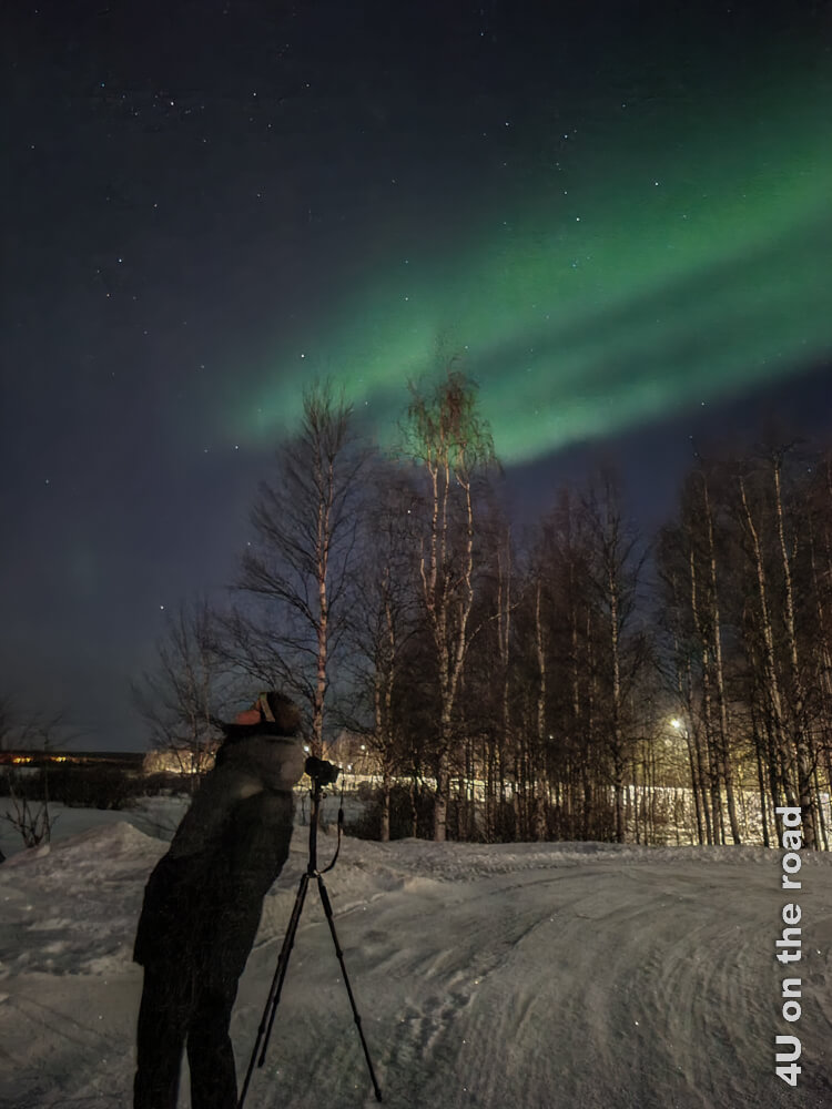 Während die Kamera die Polarlichter belichtet, schaut Jörg verträumt in den Himmel am Ufer des Ounasjoki. Auf der anderen Seite liegt das Arktikum in Rovaniemi, welches ebenfalls ein guter Platz zur Beobachtung der Polarlichter sein soll.