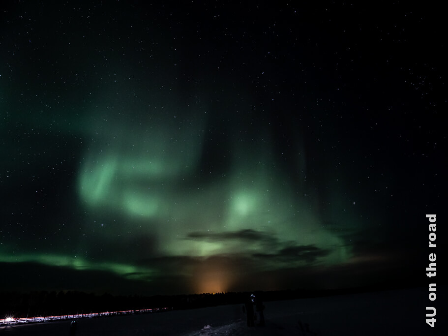 Polarlichter mit Wolken in Rovaniemi und Sternenhimmel. In diesen dunklen Gegenden sieht man gut die Lichtverschmutzung.