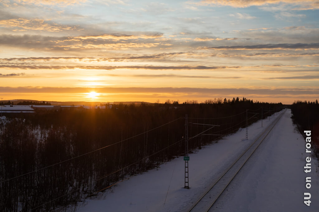 Die Gleise des Santa Claus Express führen 800 km später nach Helsinki, aber scheinbar in die Unendlichkeit. Die Sonne geht in Rovaniemi im Winter früh unter und färbt Himmel und Wolken eindrücklich.
