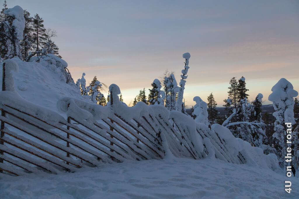 Die Zäune mit den langen schrägen Latten verwandeln sich im Winter dick zugeschneit zu eigenen Kunstwerken wie dieser Zaun im Aussengelände der Samiland Ausstellung in Levi.