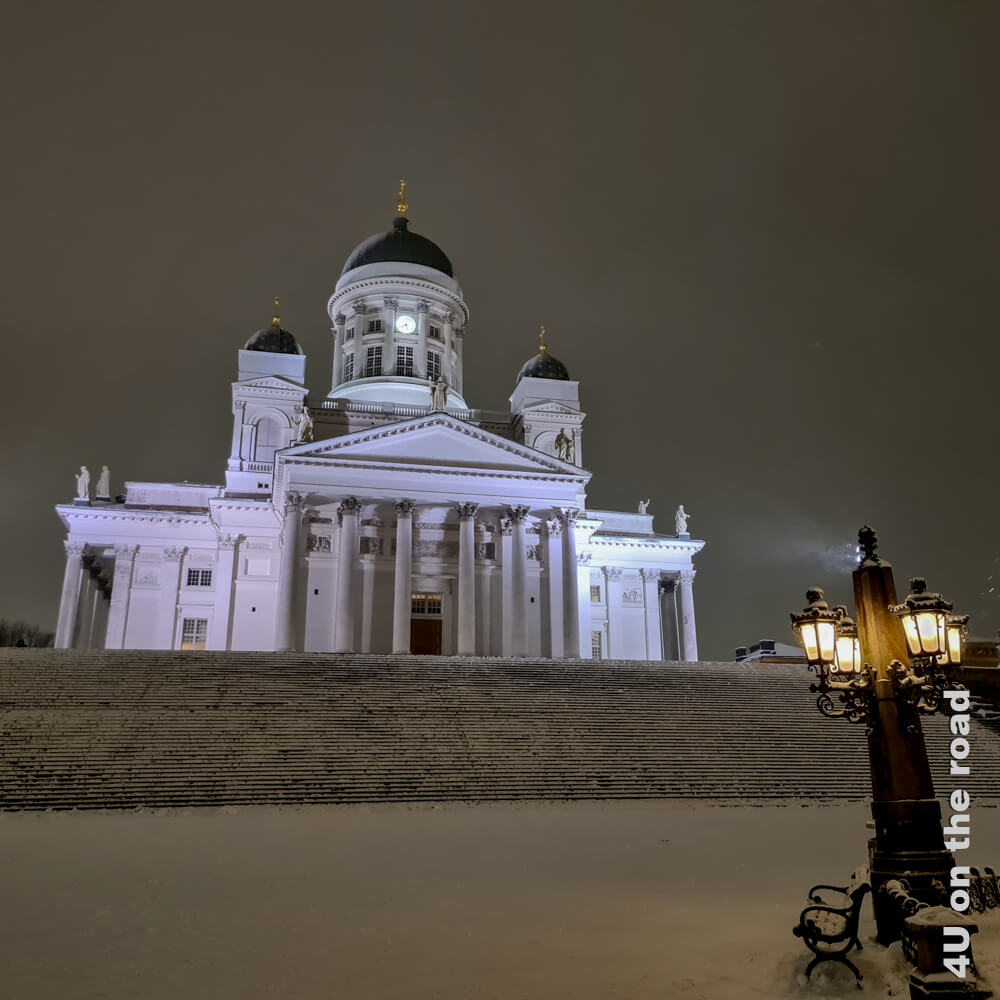 Der Dom von Helsinki, eine der Sehenswürdigkeiten von Helsinki, deren Anblick sich im Winter bei Schnee verändert, wird bei Nacht angeleuchtet.