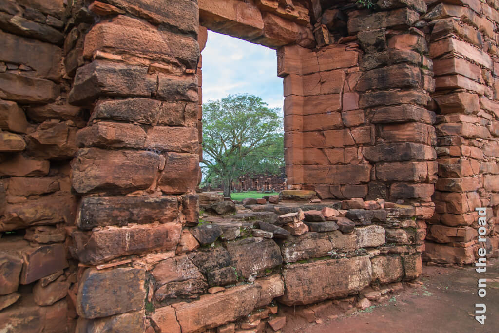 Ein Fenster in dicken Mauern lässt auf einen Platz mit grossem Baum schauen. - Jesuiten-Mission San Ignacio Mini