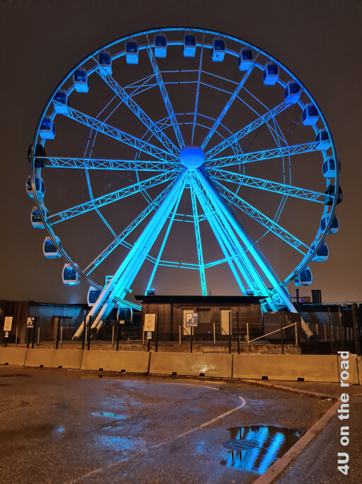 Das SkyWheel ist in der Dunkelheit blau beleuchtet. Bei Regen spiegelt sich das Riesenrad auch in den Pfützen. Helsinki Sehenswürdigkeiten im Winter