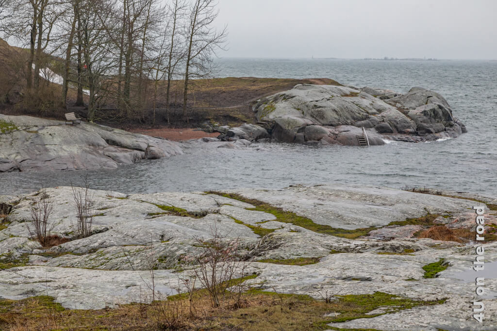 Von einem der Felsen führt eine Badeleiter ins Wasser und eine Bank lädt dazu ein, den Sonnenuntergang zu beobachten, aber jetzt im Winter ist dieser Platz auf der Seefestung Suomenlinna verwaist.